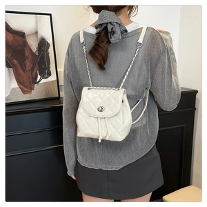 Detail of white quilted mini backpack featuring silver twist-lock and chain strap