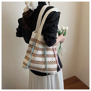 Detailed knit tote bag with striped texture and colorful tassel charms on a shoulder strap
