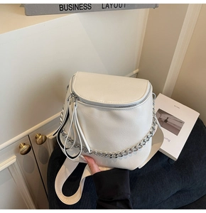 Close-up of white PU leather saddle bag with silver chain detail and wide strap