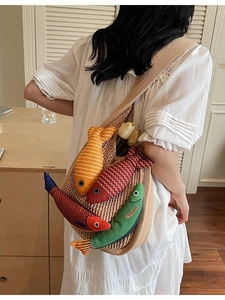 Minimalist beige woven tote bag featuring colorful fish charms shown on model shoulder