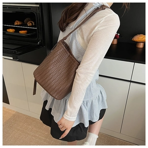 Brown woven leather bucket bag detail with adjustable strap in a lifestyle kitchen setting