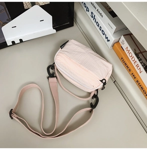 Detail of light pink plaid textured crossbody bag with adjustable strap and zipper
