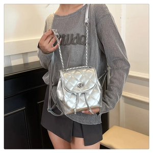Detailed view of silver quilted rhombic texture and rotating lock on metallic mini backpack