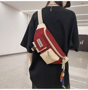 Détail du sac bandoulière rouge et crème avec sangle réglable et petit pendentif
