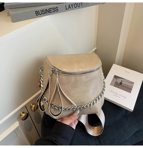 Detail of beige saddle chest bag featuring chunky silver chain and woven nylon strap