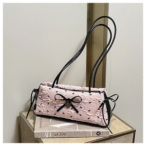 Close-up of pink quilted crossbody bag featuring black bows and a heart pendant