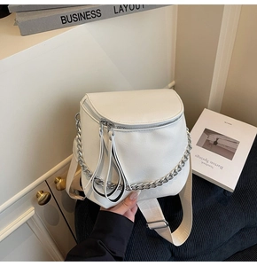 Close-up of white lychee texture leather saddle bag with silver chain and wide strap