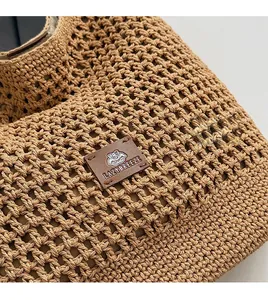 Detail of woven straw tote bag with brown leather brand patch and mesh texture