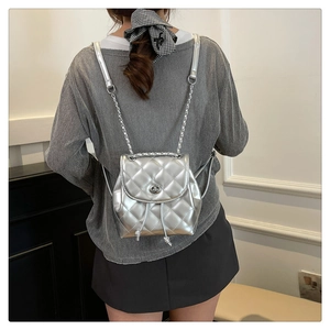 Close-up of silver quilted backpack featuring a metallic finish and elegant chain straps