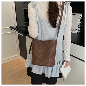Détail de la texture complexe en cuir tressé marron foncé du sac seau bandoulière