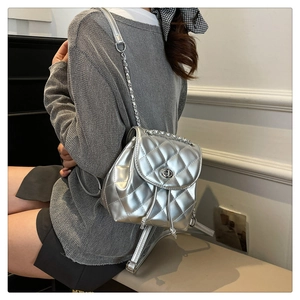 Detail view of silver quilted backpack with metal turn-lock and chain shoulder strap