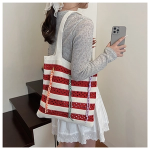 Detail of red and white striped knit tote bag with colorful plaid fringe and woven texture