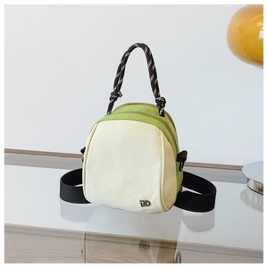 Detail of a mini two-tone cream and green handbag with a thick woven rope handle