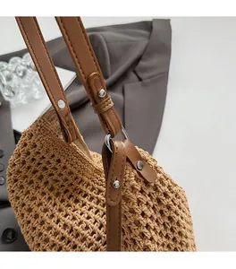 Detailed close-up of brown leather shoulder strap and polished silver metal buckle on woven bag