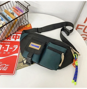 Détail du sac bandoulière bicolore avec un accessoire créatif de smiley jaune