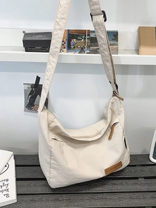 Water-resistant cream nylon crossbody hobo bag with adjustable wide strap and logo detail