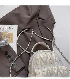 Detailed view of white quilted backpack with pearl accents and metal chain straps