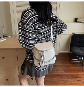 Fashionable cream white leather saddle bag featuring a chunky silver metal chain strap