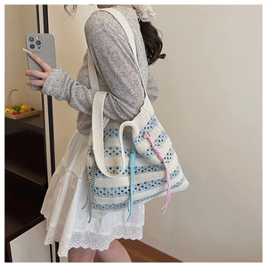 Detail of blue and beige striped knit tote bag with colorful decorative tassels