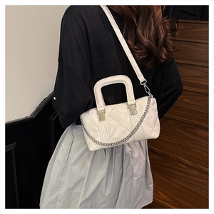 Detail of cream quilted handbag featuring high-shine finish and silver chain strap