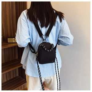 Detail of black mini backpack featuring woven handles and long decorative drawstrings