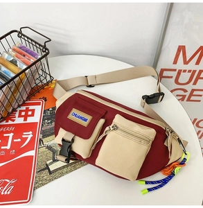 Gros plan d'un sac de poitrine en toile bordeaux avec plusieurs poches et étiquette