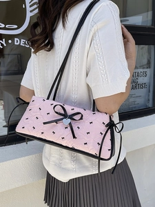 Pink quilted shoulder bag featuring black bows and heart pendant for stylish women