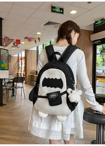 Detail eines haiförmigen Canvas-Rucksacks mit Kontrastfarben und Plüsch-Anhänger