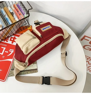 Détail d'un sac bandoulière rouge et beige avec sangle réglable sur une table blanche