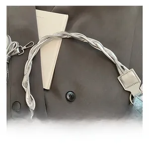 Détail de la poignée tressée argentée sur sac en jean et blazer anthracite