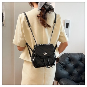 Close-up of black quilted mini backpack with silver twist-lock and chain straps
