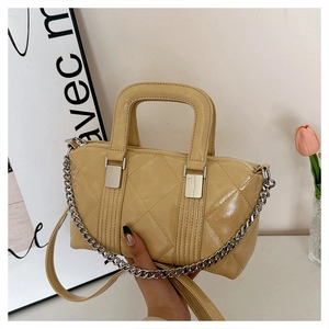 Detail of yellow quilted leather handbag with silver chain strap and top handle