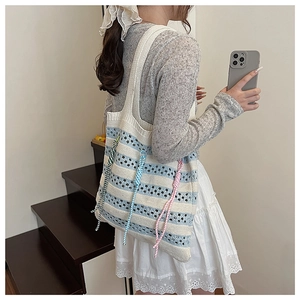 Detail of blue and white striped knit tote bag with vibrant decorative braided ropes