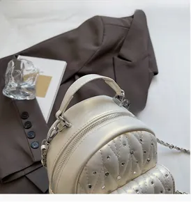 Detail of white pearl leather mini backpack with rhinestone decor and chain strap
