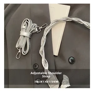 Détail de la bandoulière réglable en cuir argenté et de l'anse décorative tressée