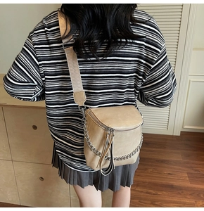 Detailed back view of a beige saddle bag with woven strap and silver chain accent