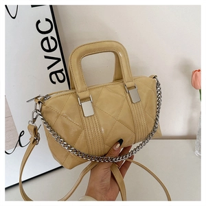 Detail of light yellow quilted patent leather bag with silver chain and handle