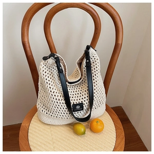 Détail du sac cabas en maille crème avec anses en cuir noir et étiquette tissée