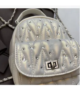 Detail of white quilted mini bag with crystal studs and silver twist lock closure