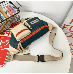 Détail d'un sac bandoulière rétro en toile vert foncé et beige avec des fermetures éclair orange