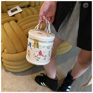 Detail of white bucket bag with colorful graffiti art and elegant gold zipper hardware
