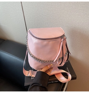 Detailed close-up of pink PU leather saddle bag with silver chain and wide nylon strap