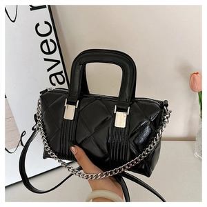Detail view of black quilted faux leather pillow bag with silver chain strap and shiny finish