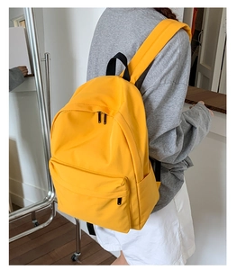 Detail of vibrant yellow lightweight backpack with side pocket and front zipper pocket