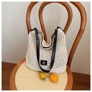 Détail de la texture du sac en tricot tissé avec poignée en cuir noir sur une chaise