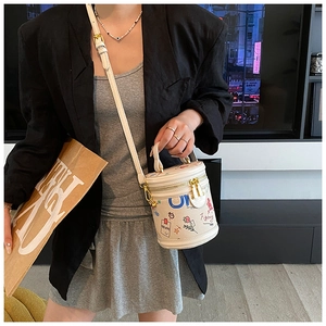 Detailed view of white cylinder bucket bag with colorful graffiti print and gold chain strap
