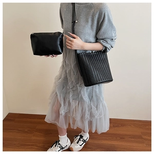 Détail d'un sac seau en cuir tressé avec pochette zippée et texture travaillée