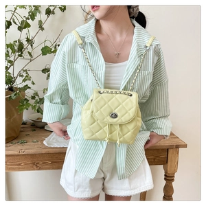 Detailed view of yellow quilted mini backpack with chain strap and twist lock closure