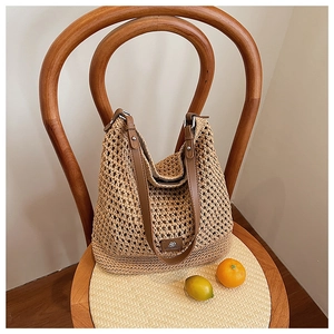 Gros plan d'un sac cabas tissé ajouré sur une chaise vintage avec bandoulière en cuir brun