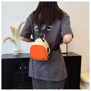 Detail view of contrast orange and beige nylon mini backpack with metal logo and rope trim